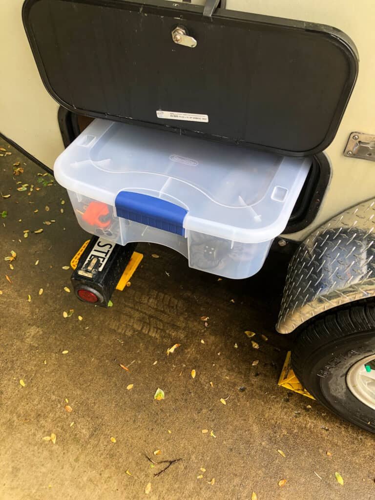 Storage compartment open to show under-bed bin